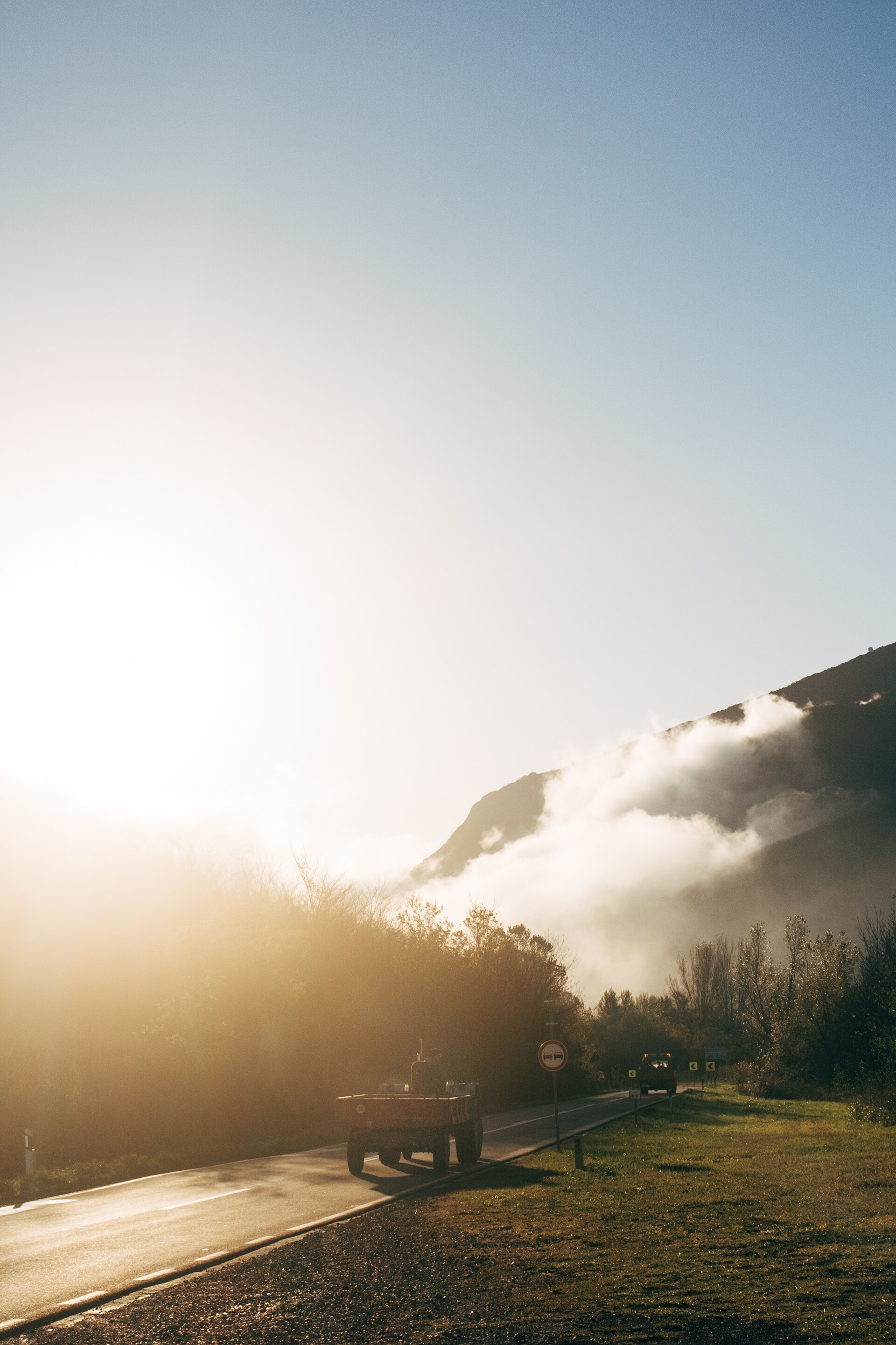A quiet road ahead at sunrise, mist rising over the mountains